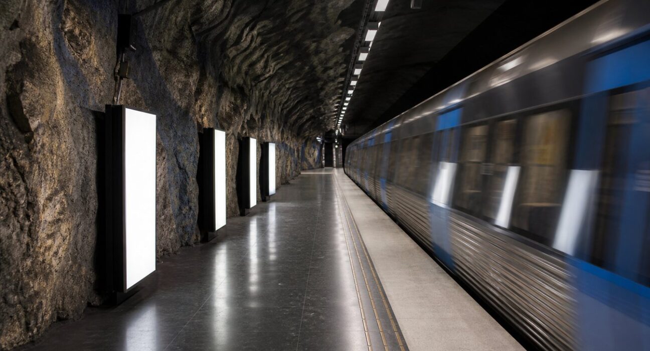 En tunnelbaneperrong i Stockholm med tomma, upplysta reklamramar längs väggen