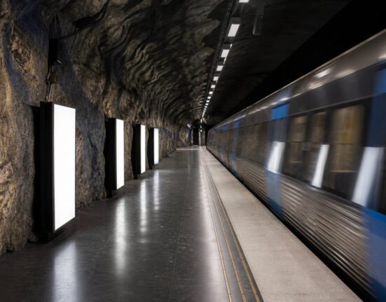 En tunnelbaneperrong i Stockholm med tomma, upplysta reklamramar längs väggen